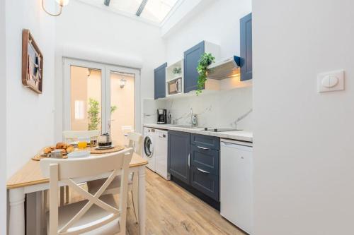 une cuisine avec des armoires bleues et une table et des chaises dans l'établissement Merry Bail Centre ville Wifi, à Douai