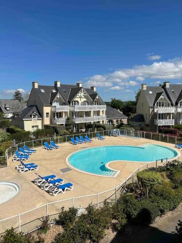 une piscine avec des chaises longues et un complexe hôtelier dans l'établissement CAP COZ Plage, à Fouesnant