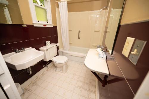 a bathroom with a white toilet and a sink at Fair Wind Motel and Cottages in Clayton
