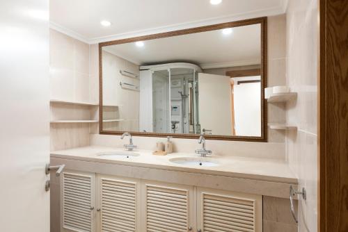 La salle de bains est pourvue de 2 lavabos et d'un grand miroir. dans l'établissement Marina Vilamoura Triplex, à Vilamoura