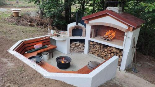 a outdoor oven with a fire pit and logs at Vikendica Verusa in Veruša