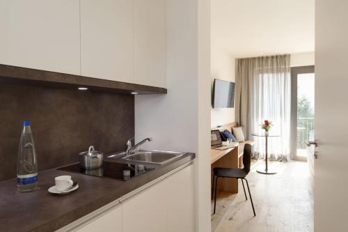 a kitchen with a sink and a desk in a room at Hotel M120 in Munich