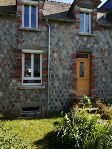 una casa de ladrillo con una puerta marrón y un patio en Chambre d hôte chez Fany en Mur-de-Bretagne