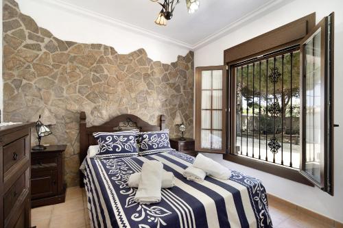 a bedroom with a blue and white bed and a window at Casa Montepinar in Chiclana de la Frontera