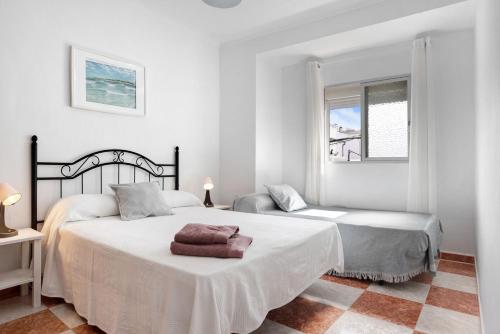 een witte slaapkamer met 2 bedden en een raam bij Casa Colomera 1 in Barbate