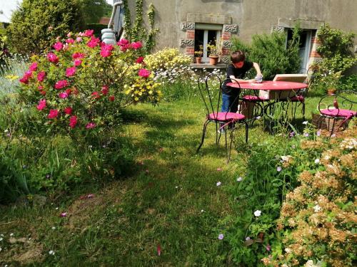 eine Person, die an einem Tisch im Garten sitzt in der Unterkunft Chambre d hôte chez Fany in Mûr-de-Bretagne