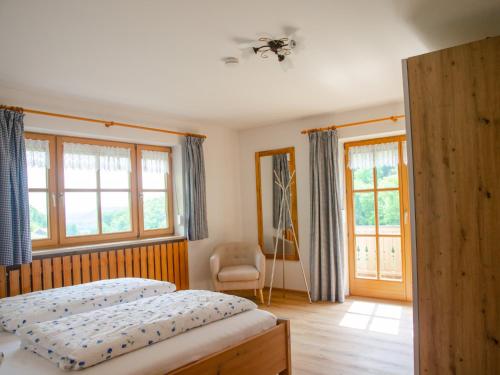 1 dormitorio con 1 cama, 1 silla y ventanas en Landhaus Mesnerbauer, en Bad Reichenhall