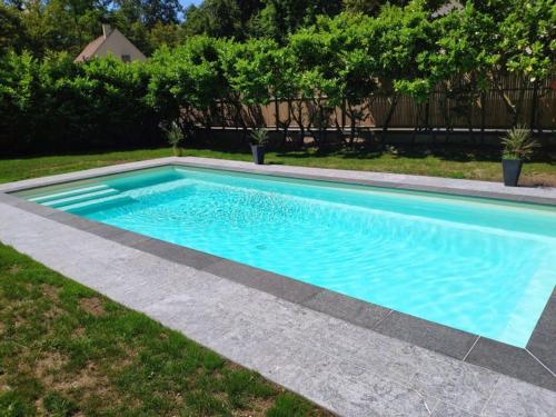 una piscina con acqua blu in un cortile di Home for Olympics a Coye-la-Forêt