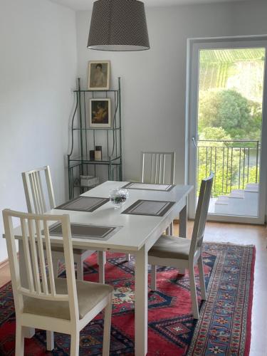 uma mesa de jantar branca com cadeiras e uma janela em Ferienwohnung FM Moselle em Reil