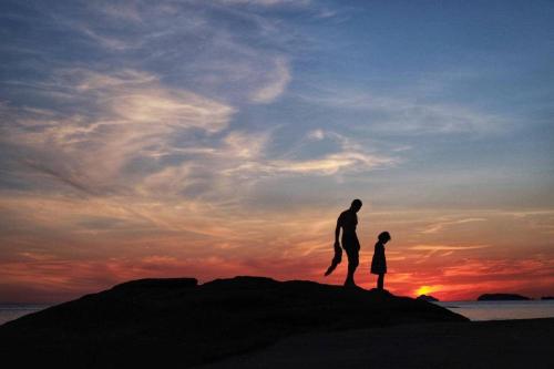 a man and a woman standing on the beach at sunset at Bird Bungalow Koh Phangan in Haad Rin