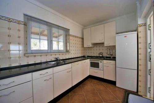 a kitchen with white cabinets and a white refrigerator at 6 Persoons Vakantiewoning Portugal - Casa do Balão - en - Casa Pequeno Pintor in Figueira e Barros