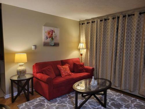a living room with a red couch and two tables at Cozy apt in center of Saint John NB in Saint John