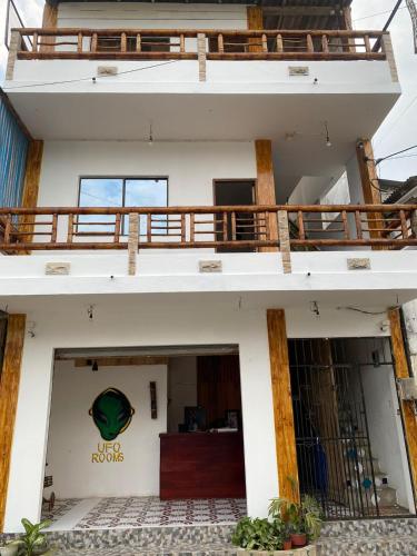a white building with a balcony on top of it at UFO Rooms in Montañita