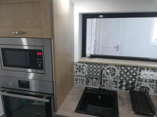 a kitchen with a microwave oven and a sink at Appartement dans maison atypique in Montrond-les-Bains