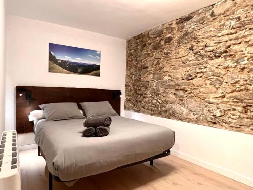 a bedroom with a bed with a stone wall at Casa Sinera - L'Amfitriona in Roní