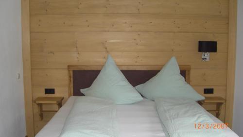 Schlafzimmer mit einem Bett mit weißer Bettwäsche und Kissen in der Unterkunft Ferienlodge Karwendelblick in Krün