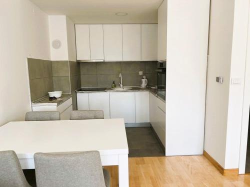 eine Küche mit weißen Schränken sowie einem weißen Tisch und Stühlen in der Unterkunft Apartment River in Bratunac
