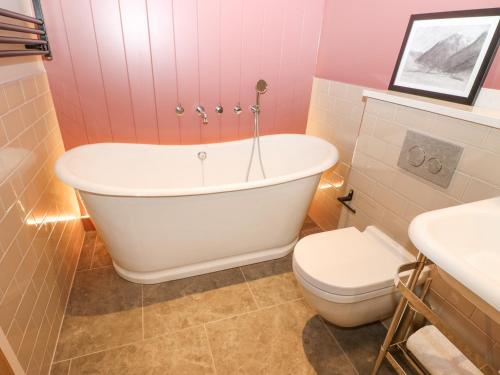 a bathroom with a white tub and a toilet at Brampton Cottage in Appleby