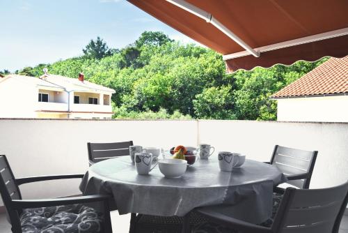 einen Tisch mit Essschüsseln auf dem Balkon in der Unterkunft Rab apartments AURORA in Rab