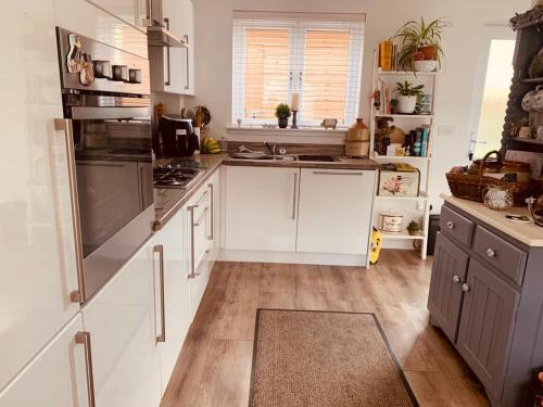 una cocina con armarios blancos y electrodomésticos de acero inoxidable en Home from home - Free Parking (near Edinburgh / Airport and Ingilston) en Edimburgo