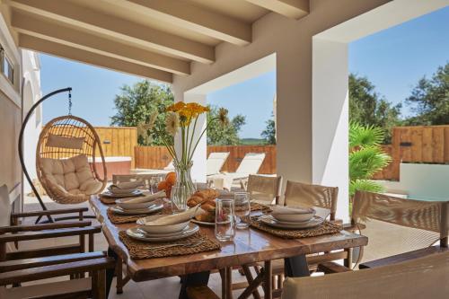 - une table en bois avec des assiettes et des verres sur la terrasse dans l'établissement Galadriel Villa, à Káto Yerakaríon