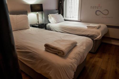 two beds in a hotel room with towels on them at Contractor Bookers At Infinity Apartments in Liverpool