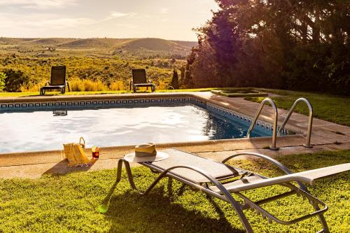 a swimming pool with two chairs and a table at CASA RURAL Cigarral del Pintor in Toledo