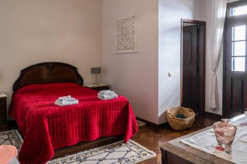 a bedroom with a red bed with a red blanket at Sunset House in Câmara de Lobos