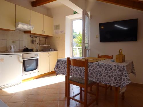 a kitchen with a table and a table and a television at Eco Apartments Kate in Suđurađ