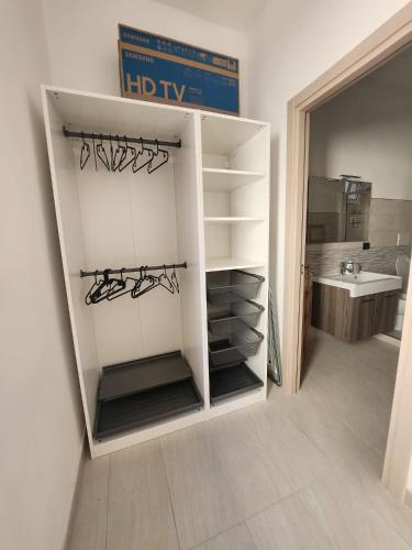 ein weißer Kleiderschrank mit Regalen und einem Waschbecken in einem Zimmer in der Unterkunft Il Pizzuto - Appartamento da Nonno Dino in Bernalda