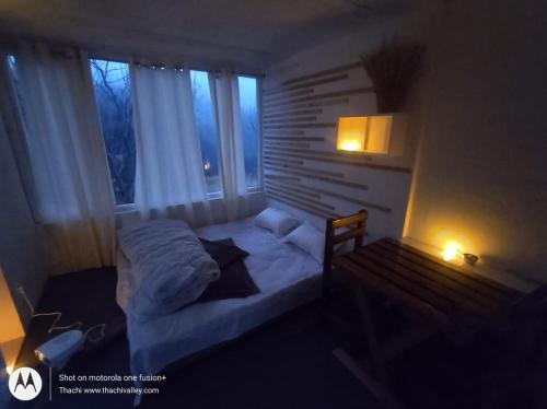um pequeno quarto com uma cama e uma janela em Stargazing Glass Lodge Himachal Pradesh Thachi em Mandi