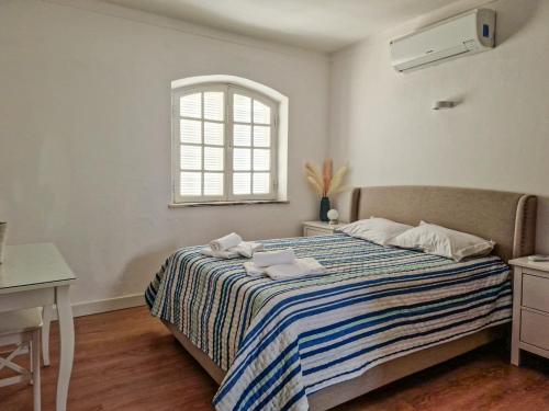 Qta do Eucalipto Villa في فارو: غرفة نوم بسرير وبطانية مخططة ونافذة