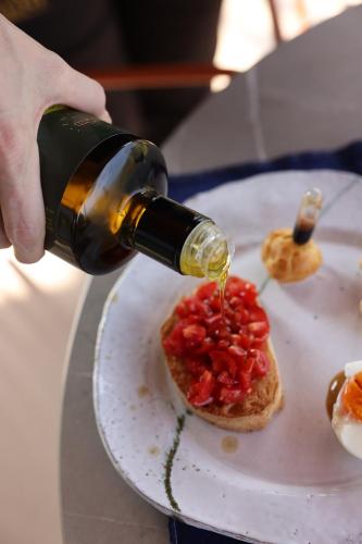 a person pouring a bottle of sauce on a piece of bread at Agriturismo Acetaia Sereni in Marano sul Panaro