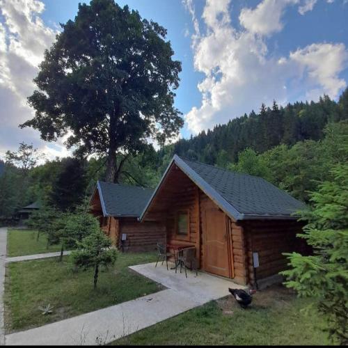 a log cabin with a table and a tree at Mulliri in Peje