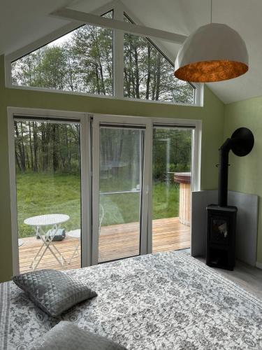 a bedroom with a bed and a fireplace in a room with glass doors at ALANTOS ŽIRGAI Holiday Villas sauna or hottube additional price in Alanta