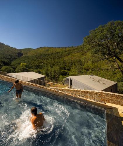 two people in a swimming pool with mountains in the background at Syntony Hotels - Paradinha Village in Arouca