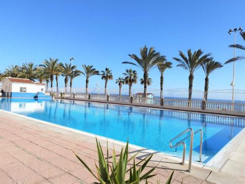 una grande piscina con palme e l'oceano di Beachfront apartment ALG-Costa a Algarrobo-Costa
