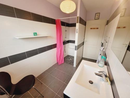 La salle de bains est pourvue d'un lavabo et d'une chaise noire. dans l'établissement La Rose des Vents, à Saint-Paul-en-Born