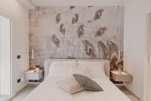 a bedroom with a white bed and a concrete wall at VillaLume in Marina di Castagneto Carducci