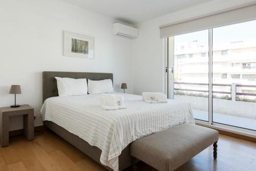 a white bedroom with a large bed and a window at Marina Vilamoura Relax Apartment in Vilamoura
