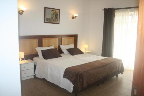 Un dormitorio con una cama grande y una ventana. en Rustic Villa Guesthouse, en Santa Bárbara de Nexe