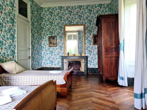 1 Schlafzimmer mit 2 Betten, einem Kamin und einem Spiegel in der Unterkunft Château de Barral in Hauterives