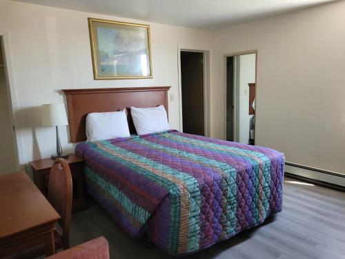 a hotel room with a large bed with a colorful blanket at Canadiana Motel in Sudbury