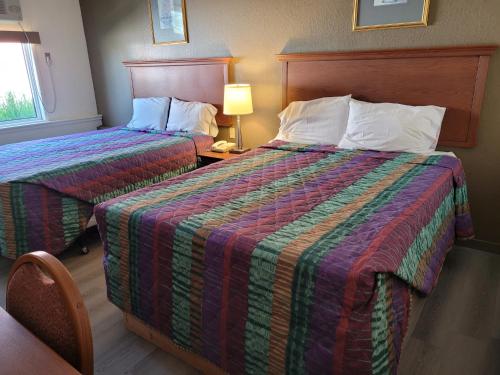 a hotel room with two beds and a lamp at Canadiana Motel in Sudbury