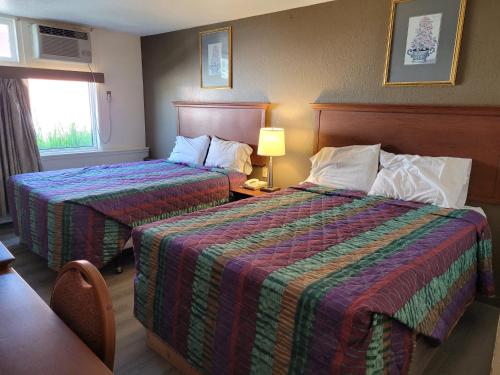 Habitación de hotel con 2 camas y ventana en Canadiana Motel, en Sudbury