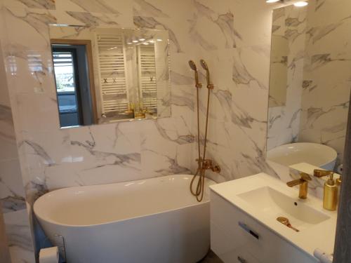 a white bathroom with a tub and a sink at Apartament Termalny na Długiej 6 in Uniejow
