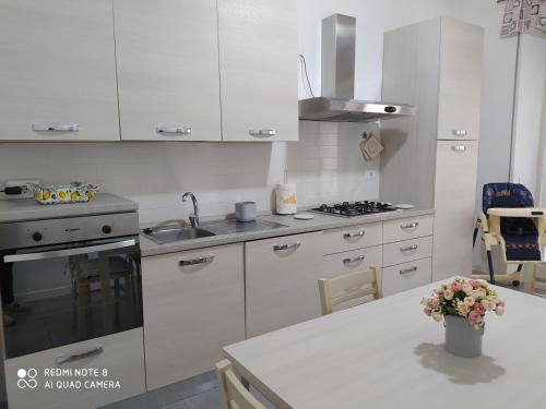 a kitchen with white cabinets and a sink and a table at casa Palmira in Orvieto