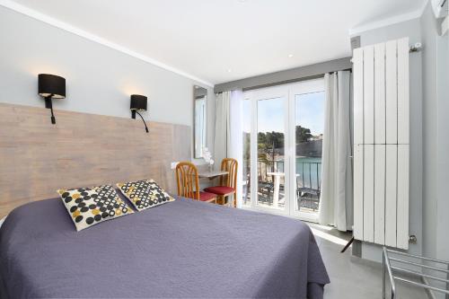 a bedroom with a bed and a table and a window at Hôtel Triton in Collioure
