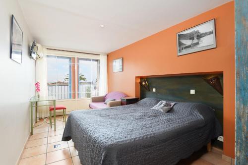 a bedroom with a bed with an orange wall at Hôtel Triton in Collioure