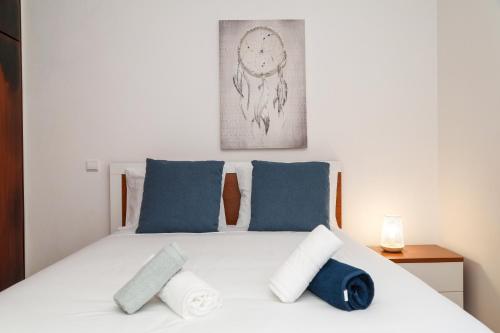 um quarto com uma cama branca e almofadas azuis em Nazaré Landscape em Nazaré